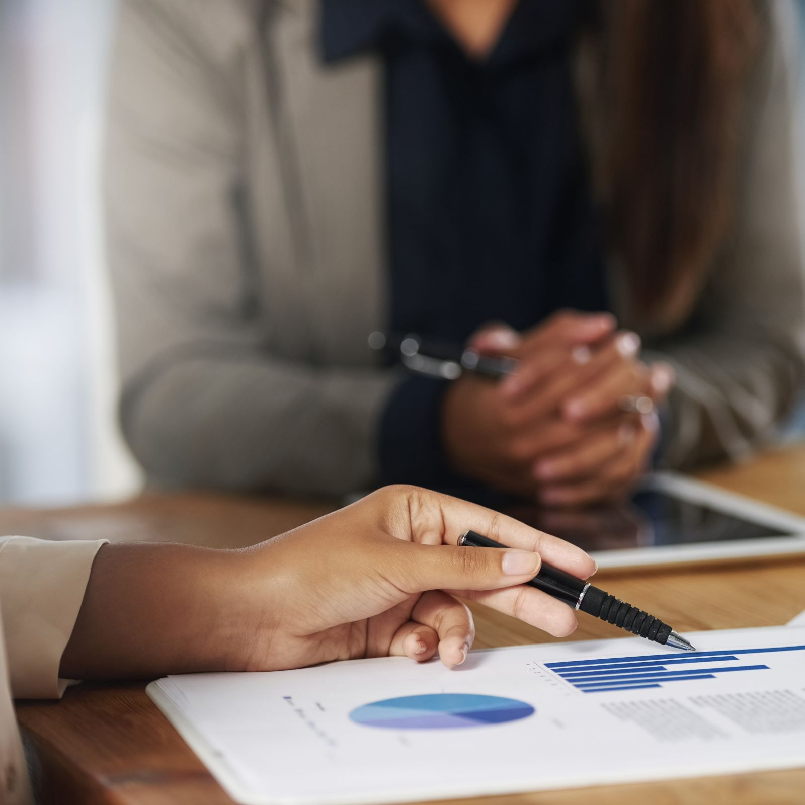 Business professional pointing a pen at sales charts during a client meeting