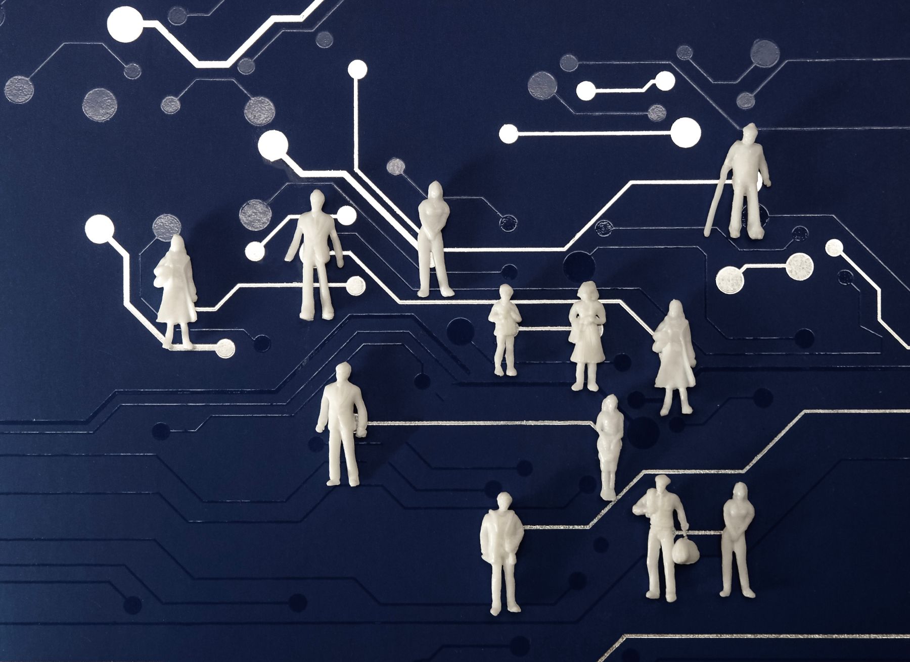 Miniature figures of people connected across a navy circuit-board network